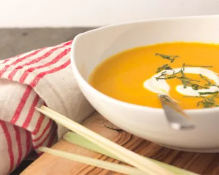 Curried Carrot and Coconut Soup in a white bowl with a spoon and a napkin