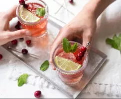 Hands grabbing Cranberry Mint Punch off a silver tray