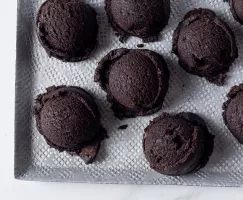 Ten scoops of edible dark chocolate cookie dough on a white tray