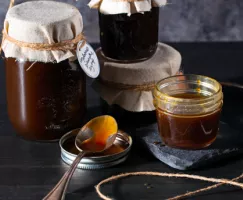 Four jars of molasses pancake syrup, one open with a spoon beside