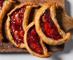 Four strawberry date galette crescents on a wooden cutting board