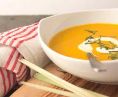 Curried Carrot and Coconut Soup in a white bowl with a spoon and a napkin